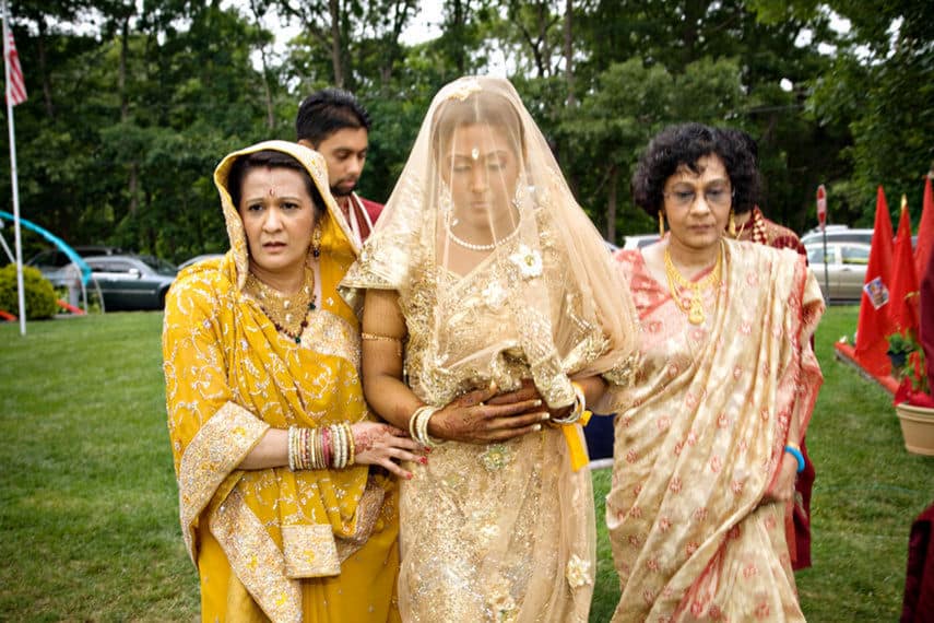 Indian bride walking down the Isle with both moms